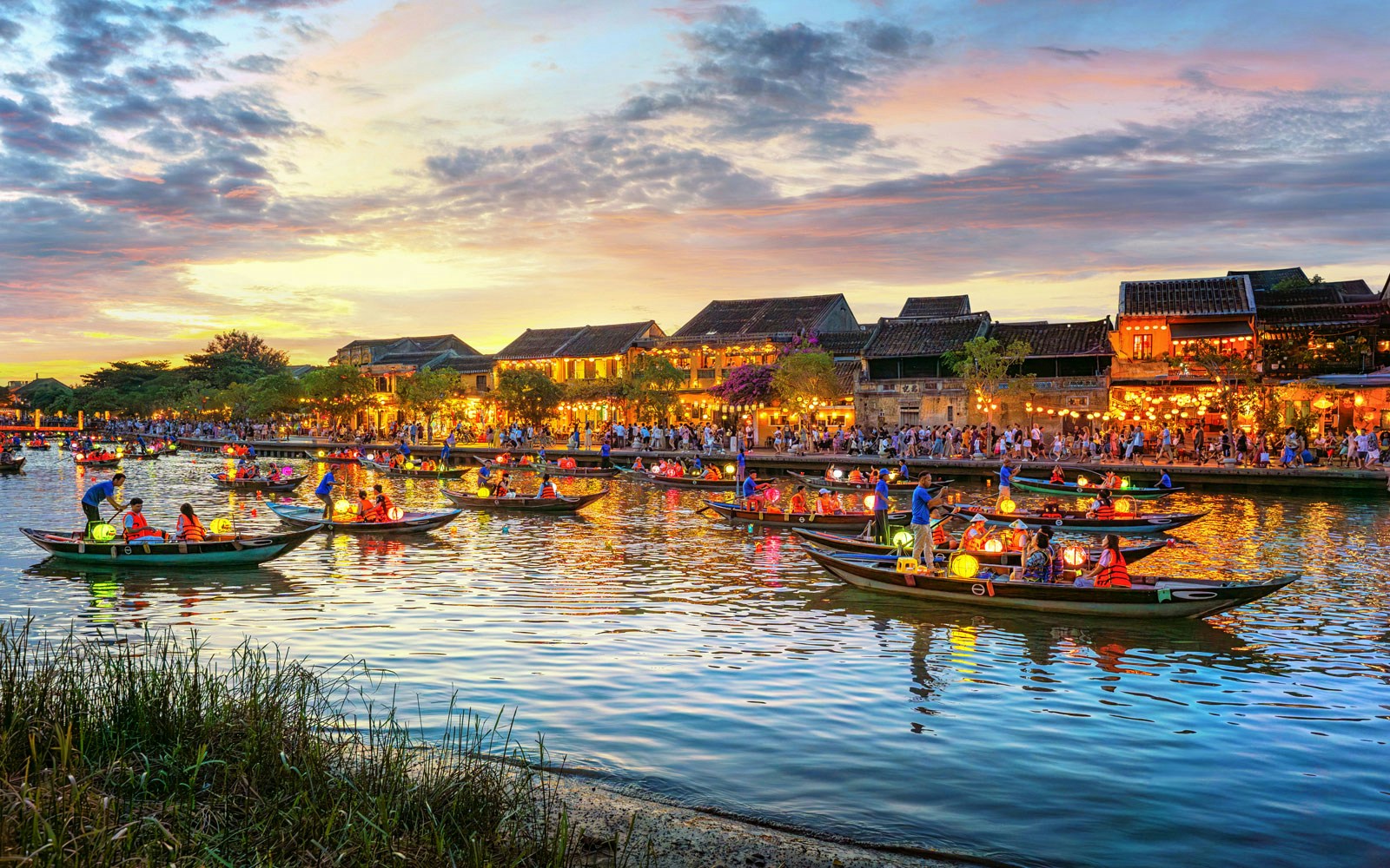 Long-tail boats with Vietnamese lanterns on the river in Hoi An, Vietnam at sunset.