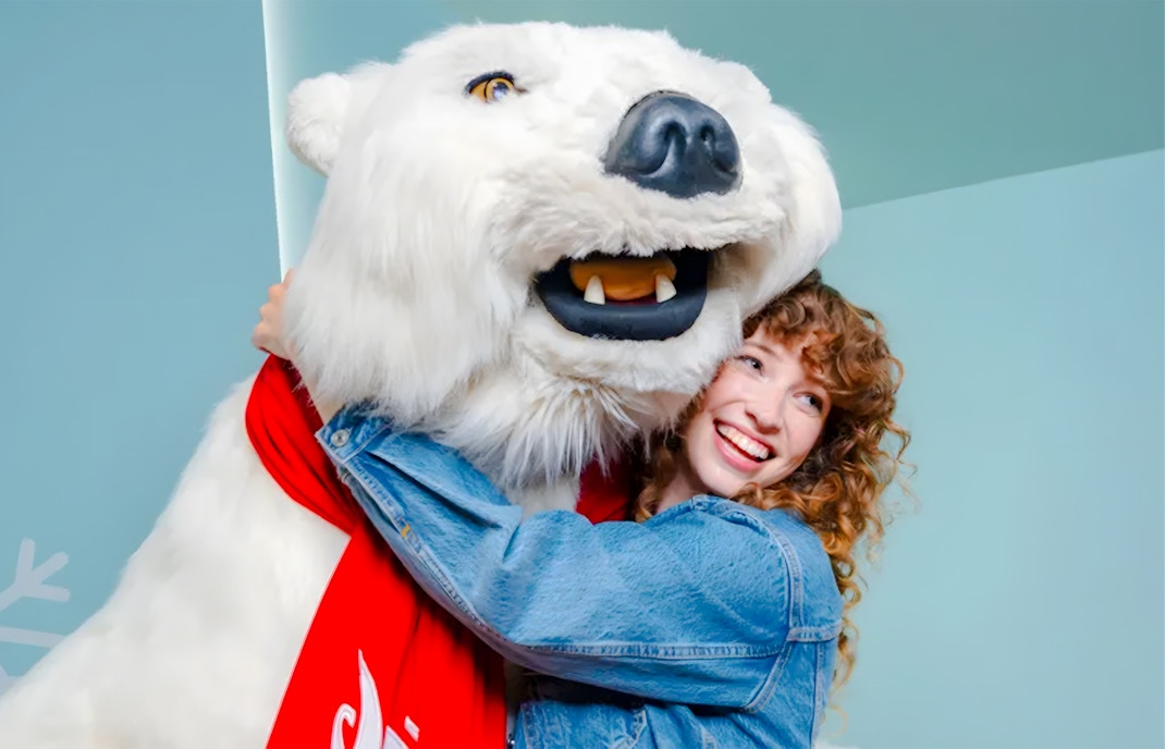 Person hugging Coca-Cola polar bear mascot at World of Coca-Cola, Atlanta.