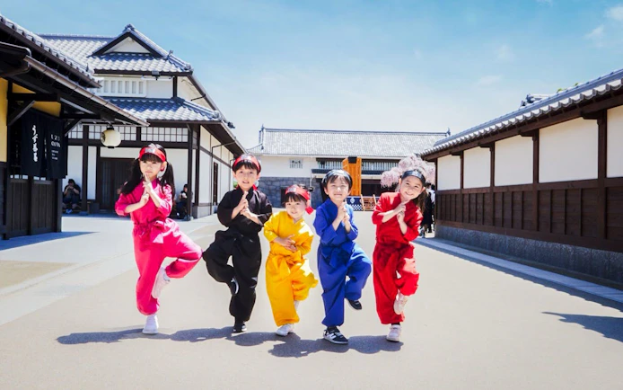 Children in colorful costumes pose at TOEI Kyoto Studio Park, Japan.