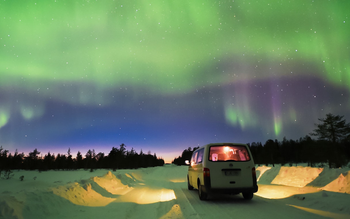 Transfer van under Northern Lights in Lapland, Finland.
