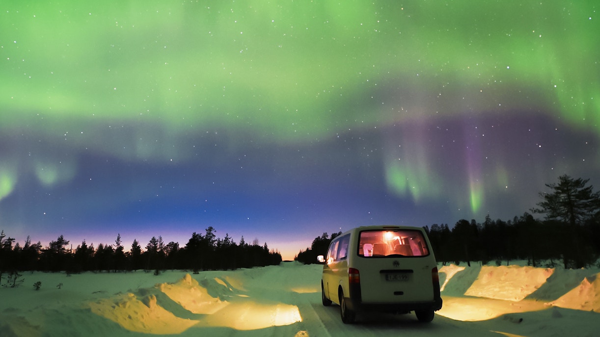 Transfer van under Northern Lights in Lapland, Finland.