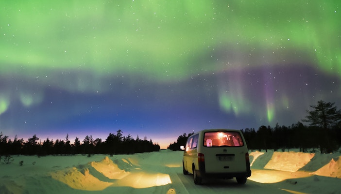 Transfer van under Northern Lights in Lapland, Finland.
