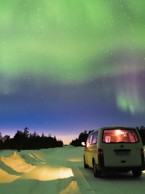 Transfer van under Northern Lights in Lapland, Finland.