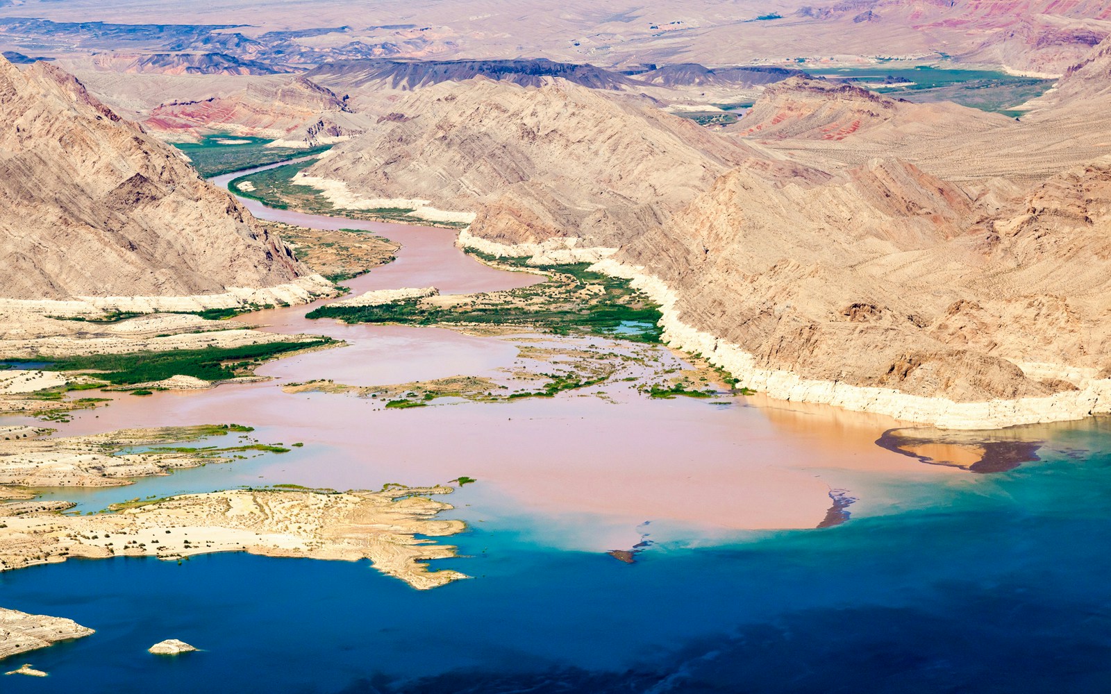 Colorado River flowing into Lake Mead surrounded by desert landscape.