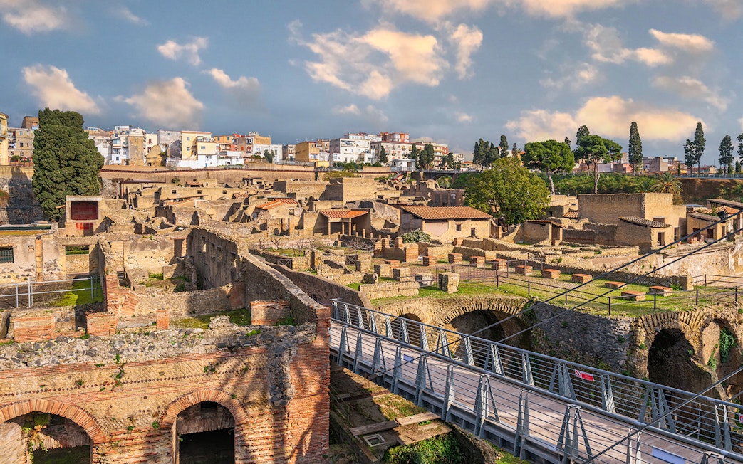 Ancient Roman ruins of Herculaneum with stone structures and modern bridge in Italy.