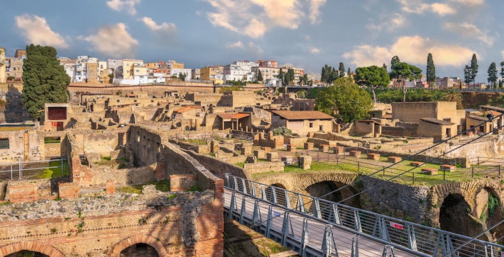 Ancient Roman ruins of Herculaneum with stone structures and modern bridge in Italy.