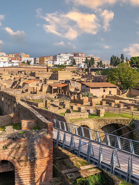 Ancient Roman ruins of Herculaneum with stone structures and modern bridge in Italy.