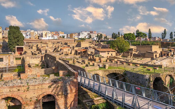 Ancient Roman ruins of Herculaneum with stone structures and modern bridge in Italy.