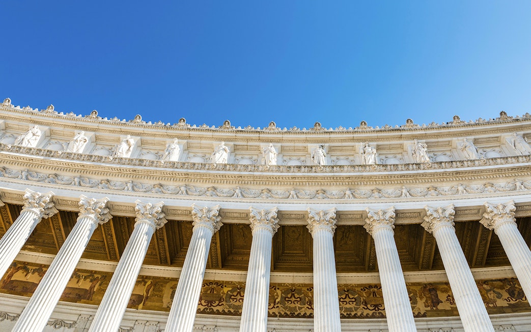 Columns and statues of Altare della Patria in Rome against a clear blue sky.