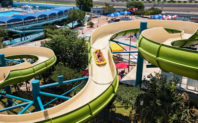 Water slide at Hurricane Harbor Arlington with people riding in a yellow raft.