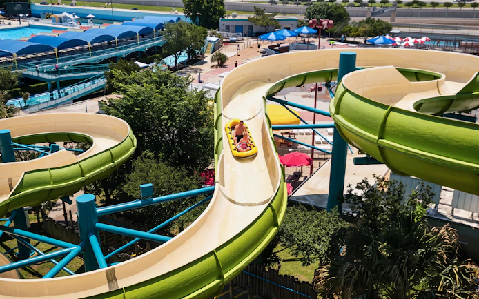 Water slide at Hurricane Harbor Arlington with people riding in a yellow raft.