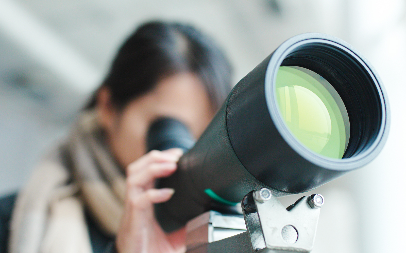 Woman observing cityscape through telescope at Griffith Observatory, Los Angeles.