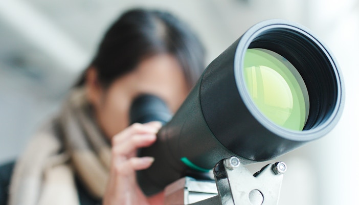 Woman observing cityscape through telescope at Griffith Observatory, Los Angeles.