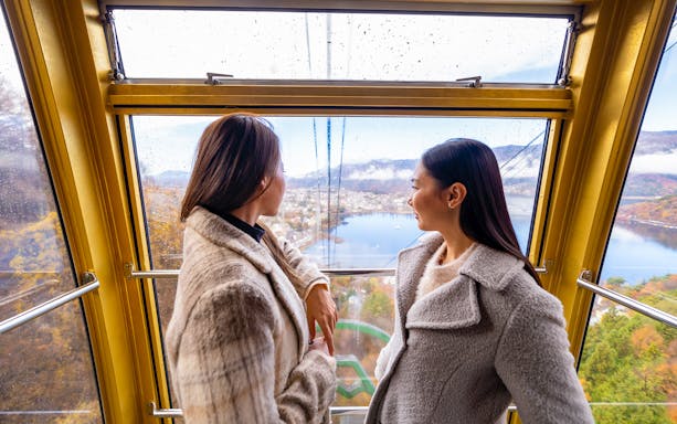 Two people enjoying the view of Lake Kawaguchi from the Mt Fuji Ropeway cabin.