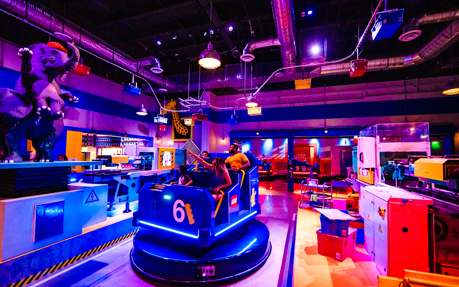 Guests enjoying a ride at Legoland New York with colorful LEGO structures and decor.