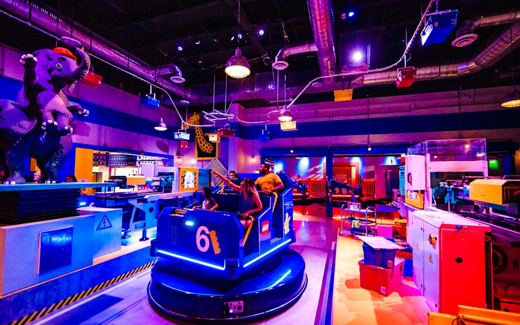 Guests enjoying a ride at Legoland New York with colorful LEGO structures and decor.