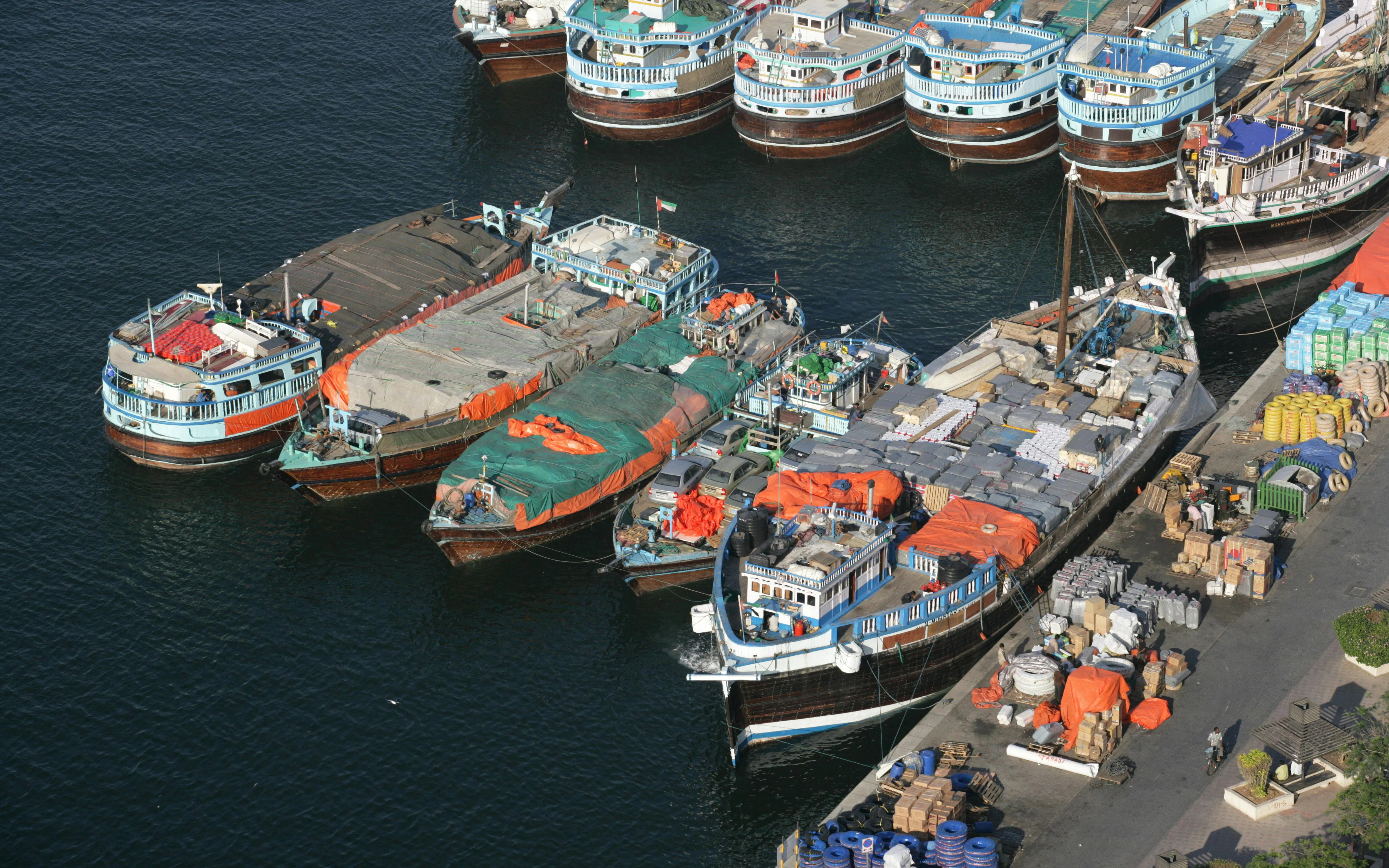 Trading dhows docked at a bustling port with goods and supplies, showcasing traditional maritime commerce.