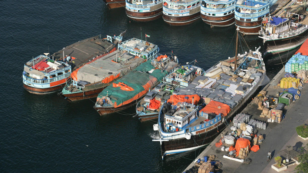 Trading dhows docked at a bustling port with goods and supplies, showcasing traditional maritime commerce.