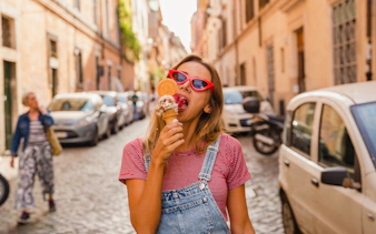Person enjoying gelato on a cobblestone street in Rome.