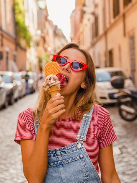 Person enjoying gelato on a cobblestone street in Rome.