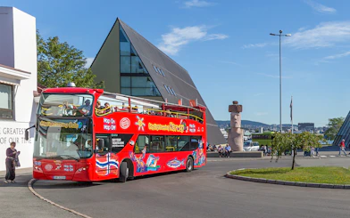 Oslo hop-on hop-off bus near modern architecture and sculpture.