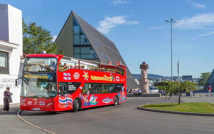 Oslo hop-on hop-off bus near modern architecture and sculpture.