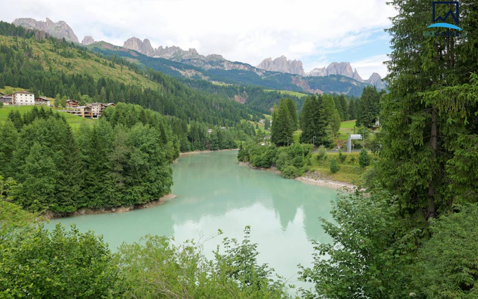 Panoramic view of Dolomites with a turquoise river and lush green forest near Verona.