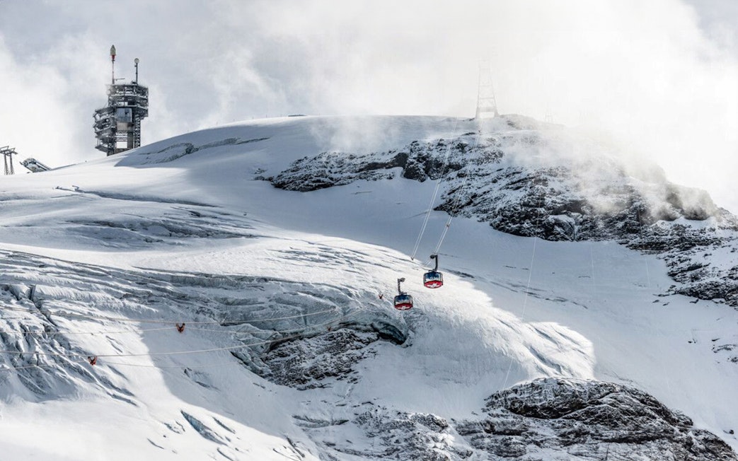 Titlis Cableways ascending snowy mountain from Engelberg, Switzerland.