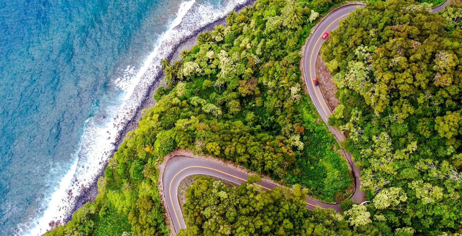 Winding coastal road through lush greenery on the Road to Hana, Maui.