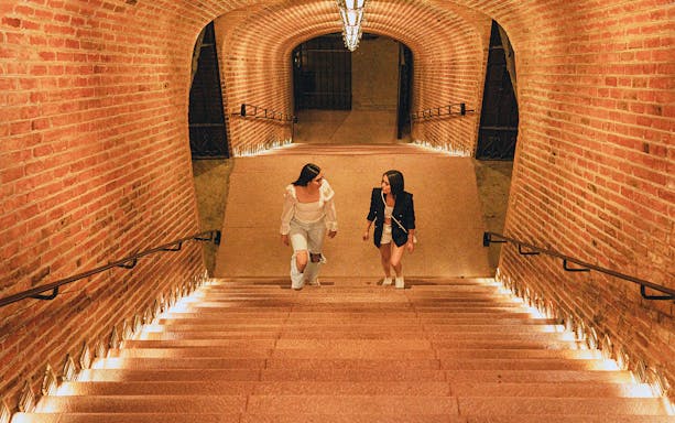Visitors walking up a brick staircase in a Queretaro wine cellar.