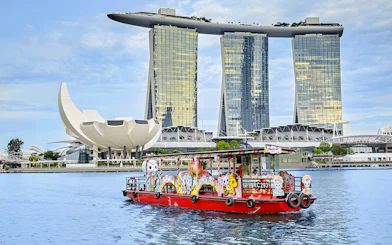 Singapore River Cruise boat with colorful designs in front of Marina Bay Sands.