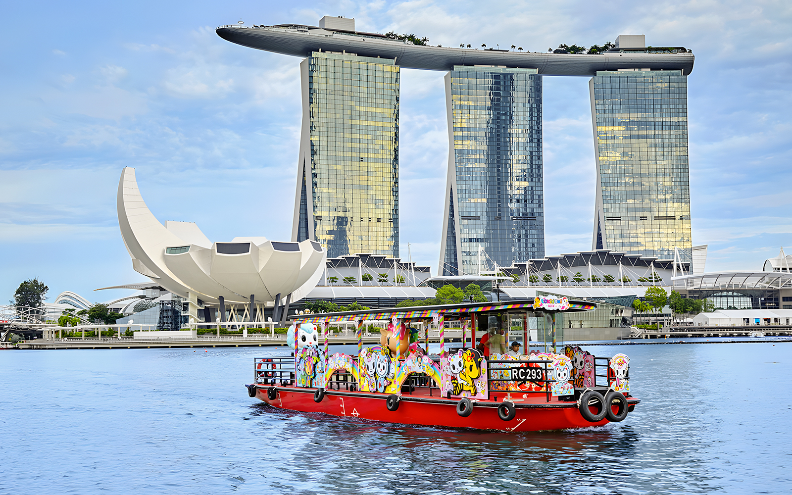 Singapore River Cruise boat with colorful designs in front of Marina Bay Sands.