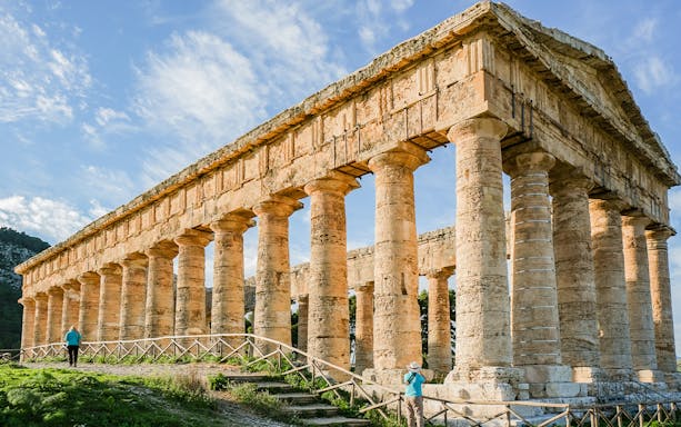 Ancient Greek temple at Segesta Archaeological Park, Sicily, with visitors exploring.