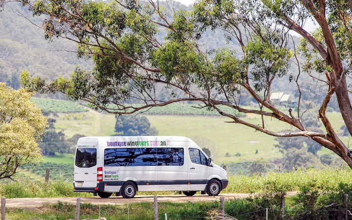Hunter Valley wine tour van driving through vineyard landscape.