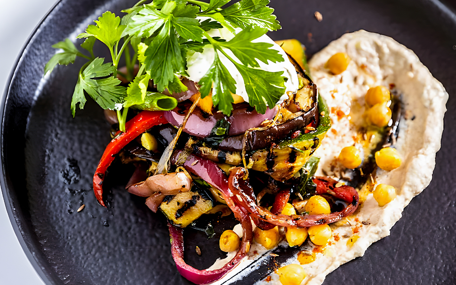 Grilled vegetables and chickpeas on a black plate during a Sydney Harbour lunch cruise.