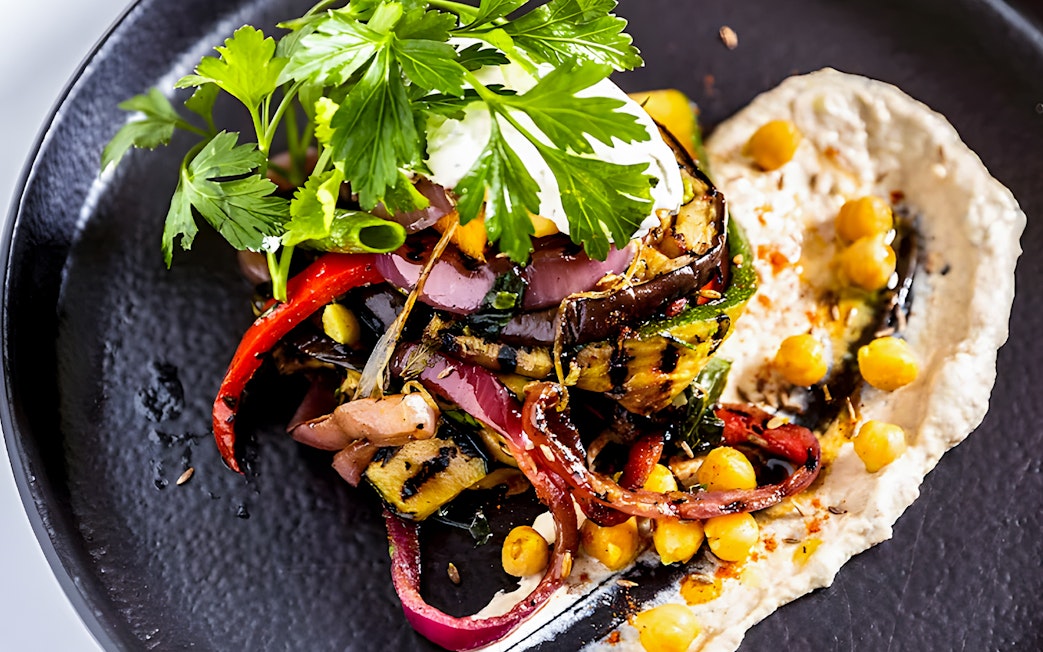 Grilled vegetables and chickpeas on a black plate during a Sydney Harbour lunch cruise.