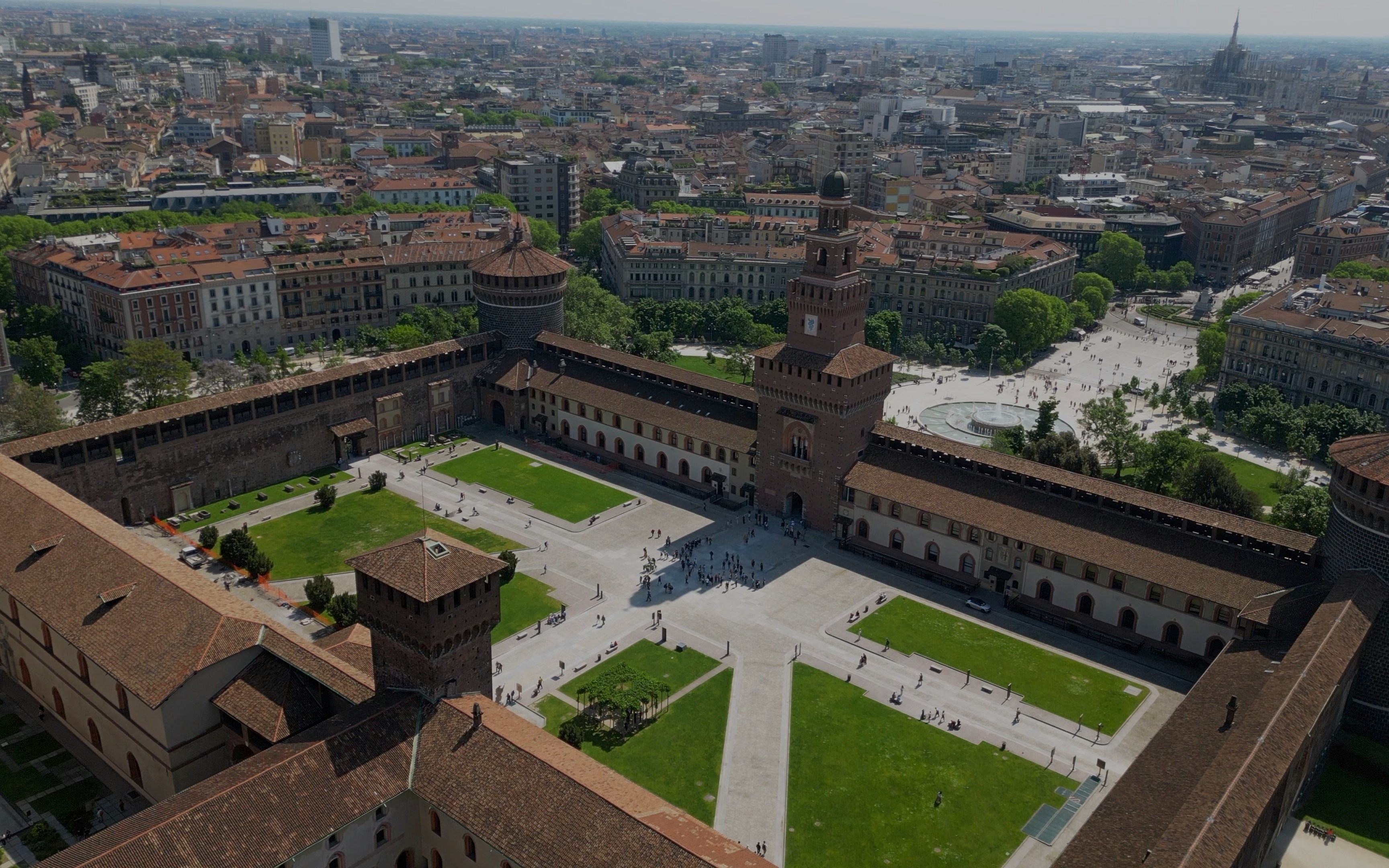 Aerial view of Sforza Castle courtyard in Milan, surrounded by historic buildings and green spaces.