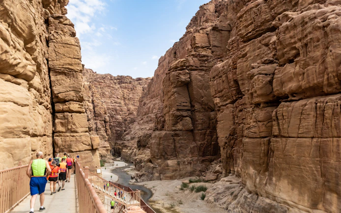 Tourists walking along a path towards Mujib River Canyon in Wadi al Mujib, Jordan.