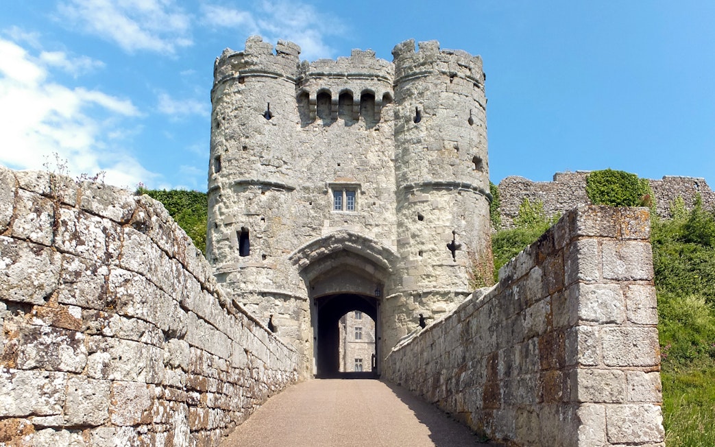 Carisbrooke Castle entrance with stone walls and towers under a blue sky.