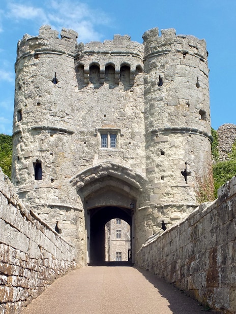 Carisbrooke Castle entrance with stone walls and towers under a blue sky.
