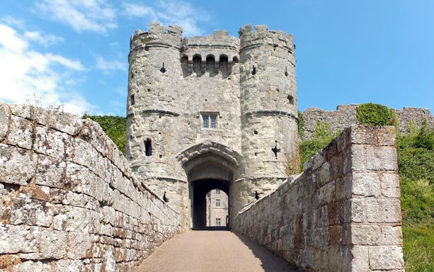 Carisbrooke Castle entrance with stone walls and towers under a blue sky.