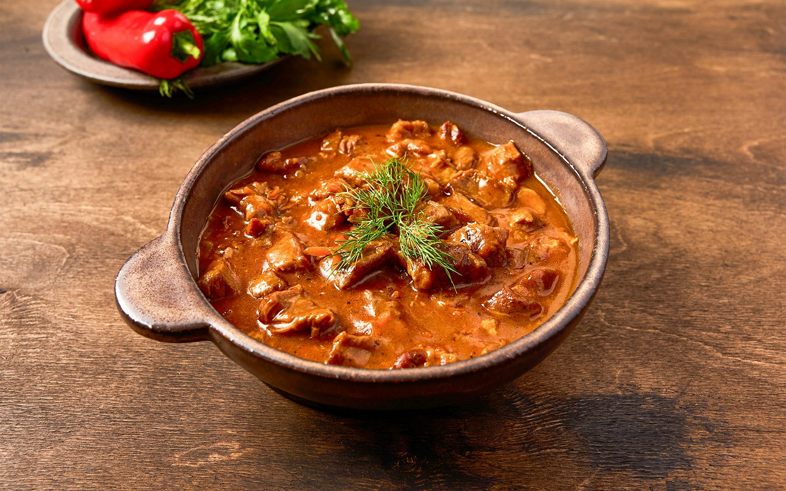 Hearty beef stew in a rustic bowl with fresh herbs, part of a foodie bucket list experience.