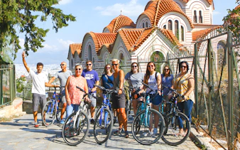 Group on bikes near Byzantine church during Acropolis guided tour in Athens.