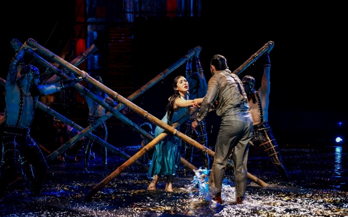 Couple performing dramatic scene at House of Dancing Water Show with bamboo poles.