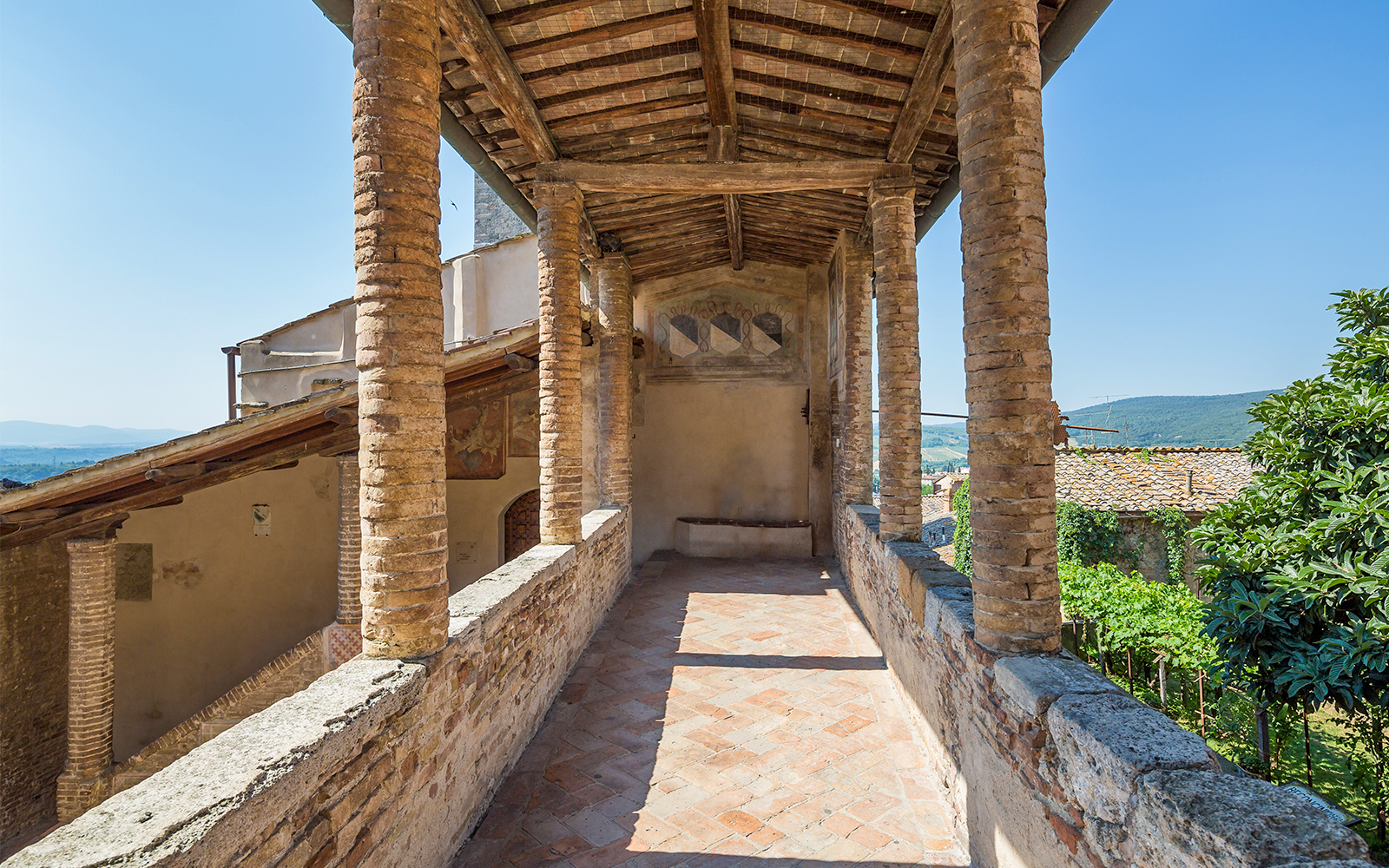 Siena Cathedral and San Gimignano Museum Pass view with rustic stone columns and countryside.