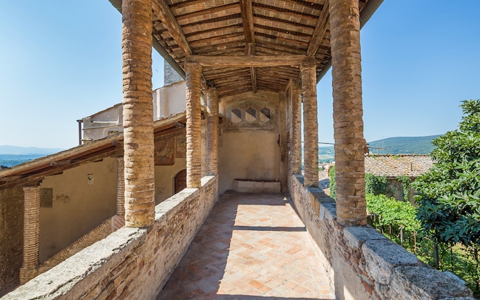 Siena Cathedral and San Gimignano Museum Pass view with rustic stone columns and countryside.