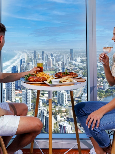 Couple dining with ocean and city views at SkyPoint Observation Deck, Gold Coast.