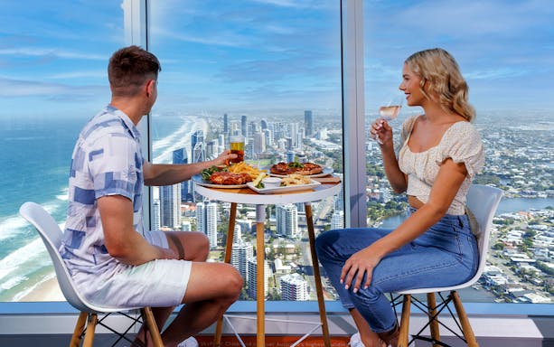 Couple dining with ocean and city views at SkyPoint Observation Deck, Gold Coast.