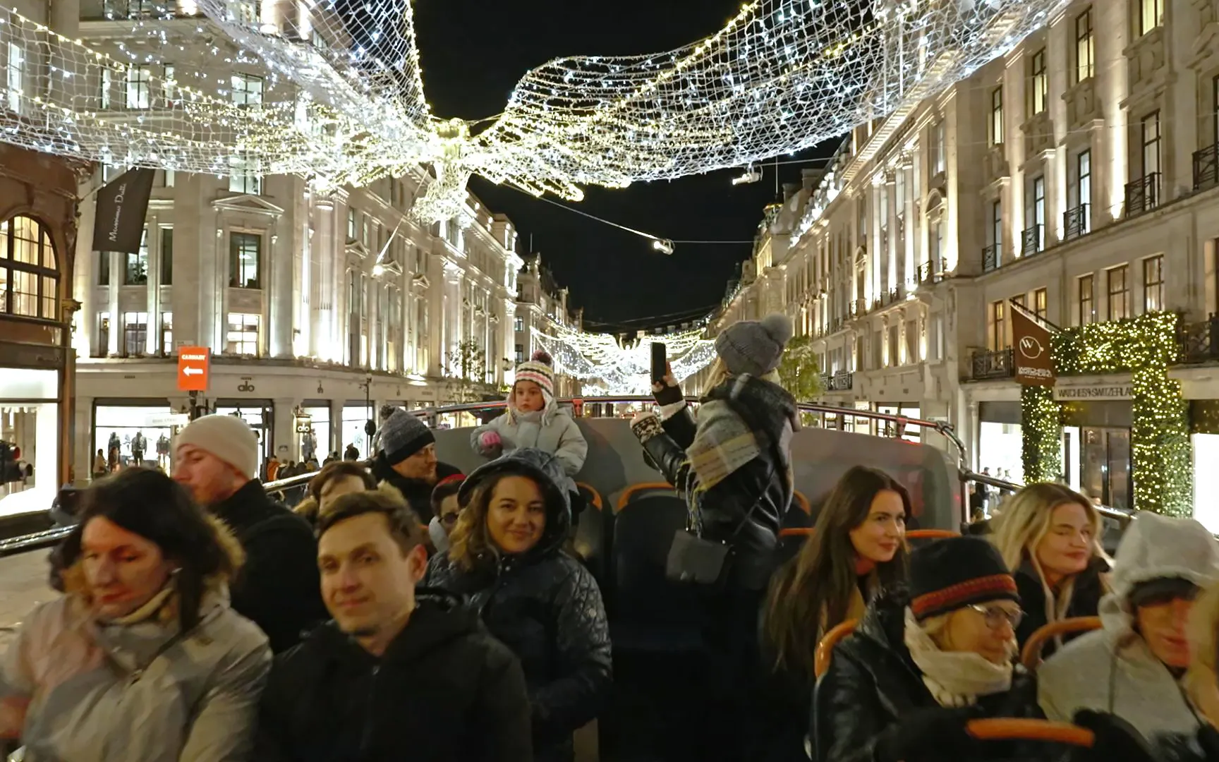 Open-top bus tour of London's Christmas lights on Regent Street at night.