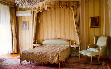 Luxurious bedroom with ornate bed and armchair inside Ceausescu Mansion, Bucharest.